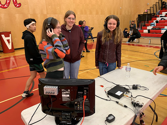 Student volunteers testing out the commentator headsets before the annual high school wrestling championships.