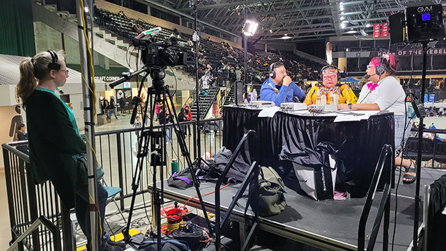 Cassandra is seen floor directing and operating a camera at the host station during the 2023 International Peace Powwow in Red Deer.